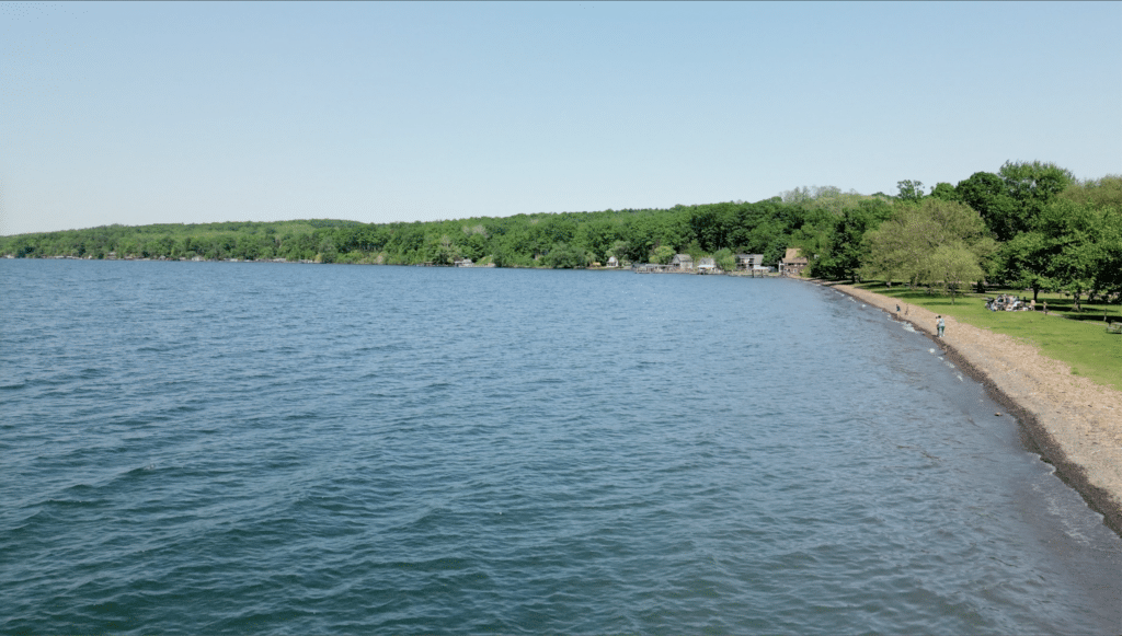 Calm Finger Lake shoreline with waterfront cottages under a clear sky